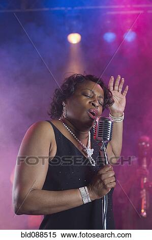 Stock Photography - Black woman singing on stage with jazz band. Fotosearch