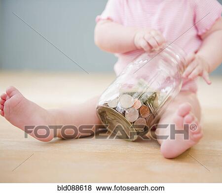Stock Photo - Caucasian baby playing with jar of coins. Fotosearch