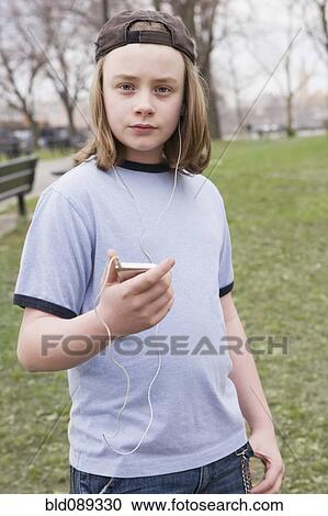 Stock Image - Caucasian boy listening to mp3 player in park. Fotosearch