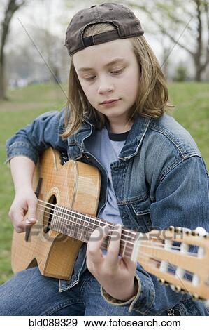 Stock Photo - Caucasian boy playing acoustic guitar. Fotosearch