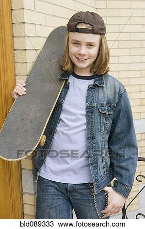 Stock Image - Caucasian boy standing with skateboard. Fotosearch
