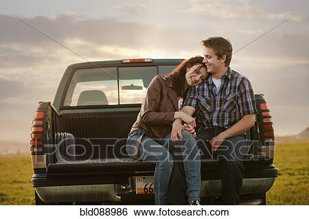 Stock Photograph - Caucasian couple hugging in back of truck. Fotosearch