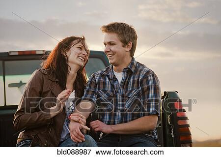Stock Photo - Caucasian couple sitting in back of truck. Fotosearch