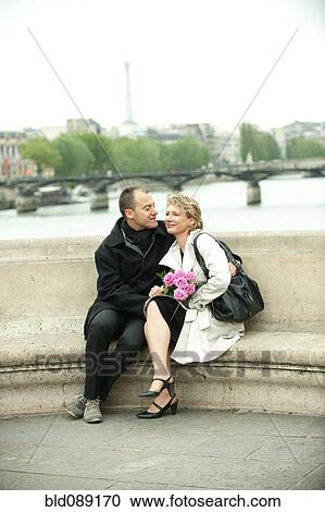Caucasian couple sitting on bench on bridge View Large Photo Image Stock Image - Caucasian couple sitting on bench on bridge. Fotosearch
