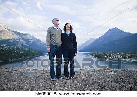 Stock Photography - Caucasian couple standing outdoors with mountains in background. Fotosearch