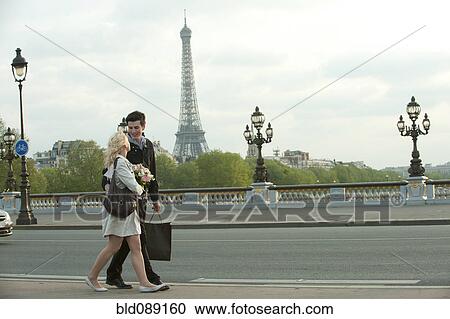 Caucasian couple walking across bridge with Eiffel Tower in background View Large Photo Image Stock Image - Caucasian couple walking across bridge with Eiffel Tower in background. Fotosearch