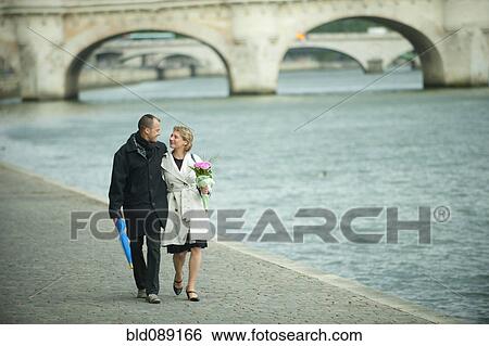 Caucasian couple walking near city river View Large Photo Image Stock Photograph - Caucasian couple walking near city river. Fotosearch