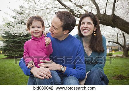 Stock Image - Caucasian family sitting together outdoors. Fotosearch
