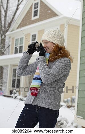 Picture - Caucasian girl taking photographs in snow. Fotosearch