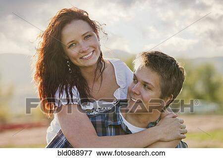 Stock Photo - Caucasian man giving girlfriend piggyback ride. Fotosearch