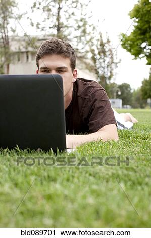Caucasian man using laptop in grass View Large Photo Image Stock Image - Caucasian man using laptop in grass. Fotosearch