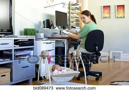 Caucasian mother working in home office with baby next to her View Large Photo Image Stock Image - Caucasian mother working in home office with baby next to her. Fotosearch