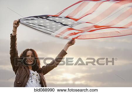 Caucasian woman holding flapping American flag View Large Photo Image Stock Image - Caucasian woman holding flapping American flag. Fotosearch