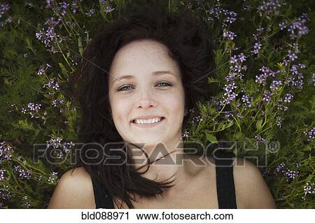 Stock Image - Caucasian woman laying in flowers. Fotosearch