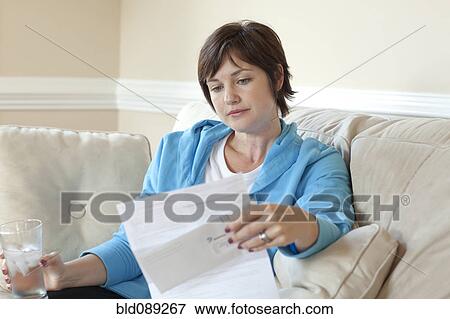 Caucasian woman on sofa reviewing bills View Large Photo Image Stock Photo - Caucasian woman on sofa reviewing bills. Fotosearch