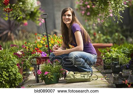 Caucasian woman squatting with flowers in plant nursery View Large Photo Image Stock Photo - Caucasian woman squatting with flowers in plant nursery. Fotosearch