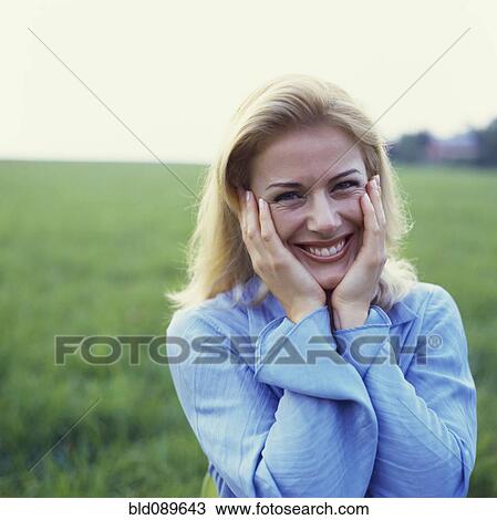Stock Image - Caucasian woman standing in green field. Fotosearch