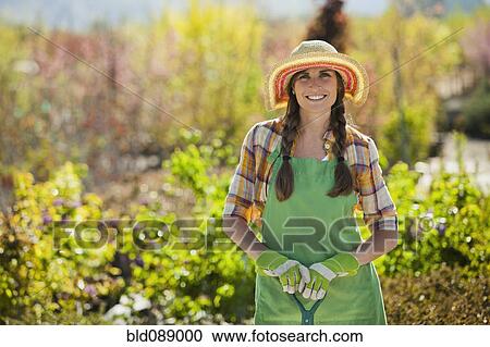 Stock Image - Caucasian woman standing with shovel in plant nursery. Fotosearch