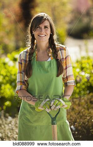 Stock Photo - Caucasian woman standing with shovel in plant nursery. Fotosearch