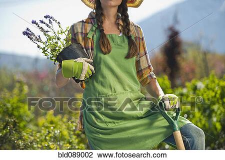 Caucasian woman standing with shovel and flowers in plant nursery View Large Photo Image Stock Image - Caucasian woman standing with shovel and flowers in plant nursery. Fotosearch