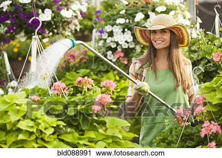 Stock Image - Caucasian woman watering plants. Fotosearch