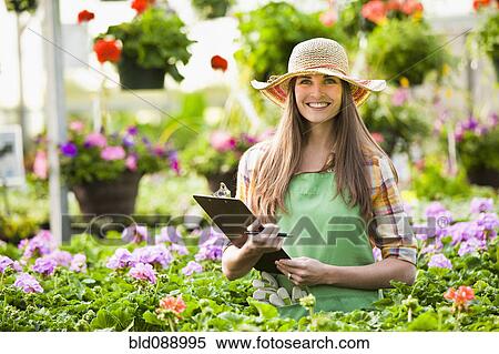 Stock Photography - Caucasian woman working in plant nursery. Fotosearch