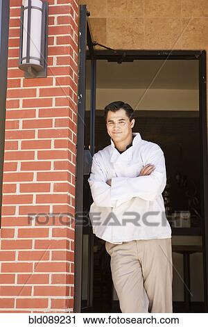 Stock Image - Chinese chef standing in restaurant doorway. Fotosearch