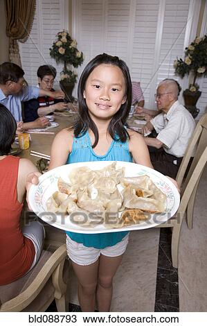 Stock Image - Chinese girl serving family dumplings. Fotosearch