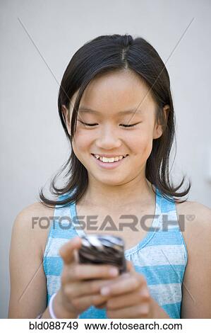 Stock Photo - Chinese girl text messaging on cell phone. Fotosearch