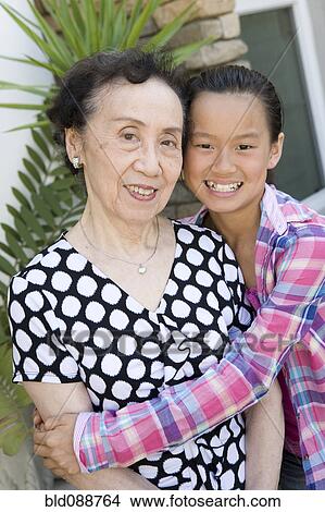 Picture - Chinese granddaughter hugging grandmother. Fotosearch