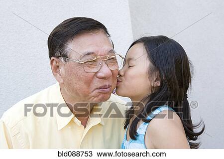 Stock Image - Chinese granddaughter kissing grandfather. Fotosearch