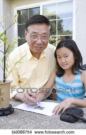 Picture - Chinese grandfather teaching granddaughter calligraphy. Fotosearch
