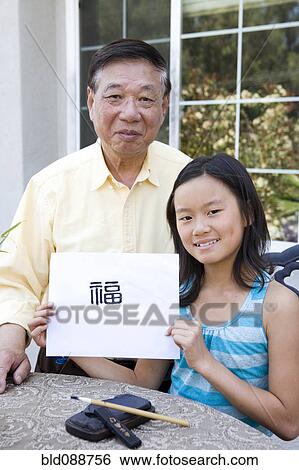 Stock Photograph - Chinese grandfather teaching granddaughter calligraphy. Fotosearch