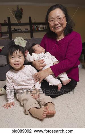Stock Image - Chinese grandmother sitting with granddaughters. Fotosearch