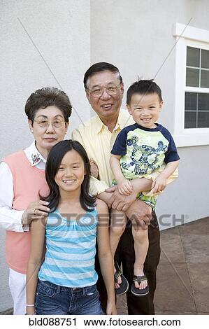 Stock Image - Chinese grandparents standing with grandchildren. Fotosearch