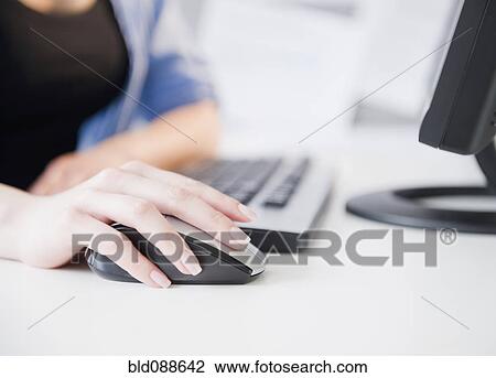 Stock Image - Close up of Korean woman using computer mouse. Fotosearch