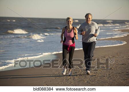 Picture - Couple running together on beach. Fotosearch