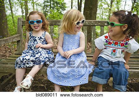Girls in sunglasses sitting on bench together View Large Photo Image Stock Image - Girls in sunglasses sitting on bench together. Fotosearch
