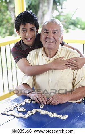 Stock Photograph - Grandfather and grandson playing dominoes. Fotosearch