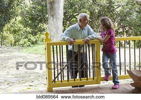 Picture - Grandfather talking to granddaughter on porch. Fotosearch