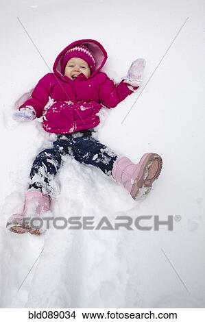 Picture - Grinning girl laying in snow. Fotosearch