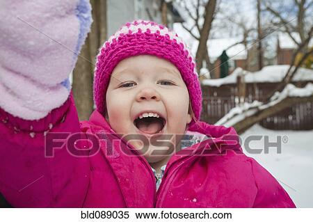 Stock Photography - Grinning girl playing in snow. Fotosearch