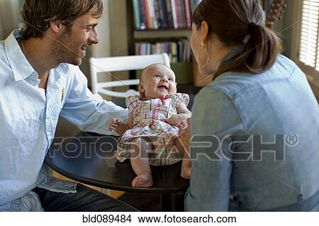 Picture - Happy Caucasian parents admiring baby daughter. Fotosearch