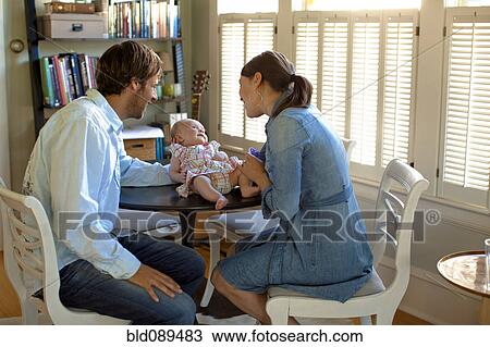 Stock Image - Happy Caucasian parents admiring baby daughter. Fotosearch