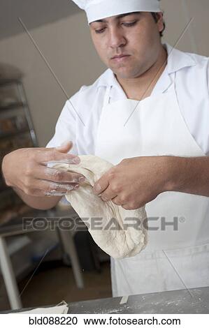 Stock Image - Hispanic baker working in commercial kitchen. Fotosearch