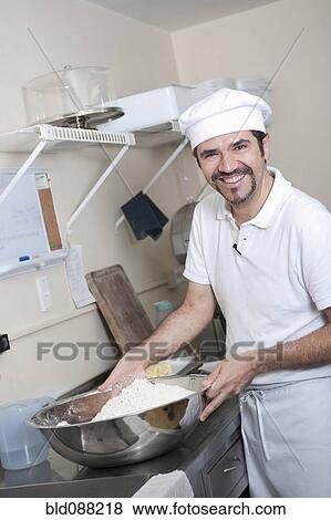Stock Photo - Hispanic baker working in commercial kitchen. Fotosearch