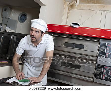 Stock Photo - Hispanic baker working in commercial kitchen. Fotosearch