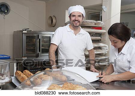 Stock Image - Hispanic bakers working in commercial kitchen. Fotosearch