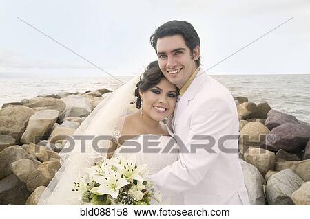 Stock Photo - Hispanic bride and groom hugging. Fotosearch