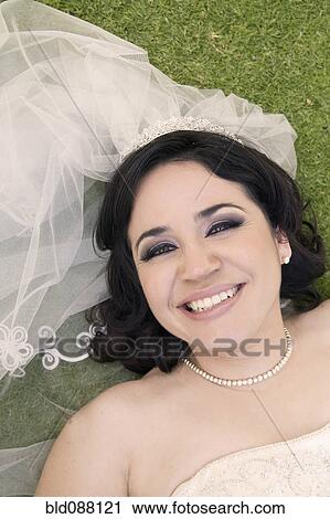 Hispanic bride laying in grass View Large Photo Image Stock Image - Hispanic bride laying in grass. Fotosearch